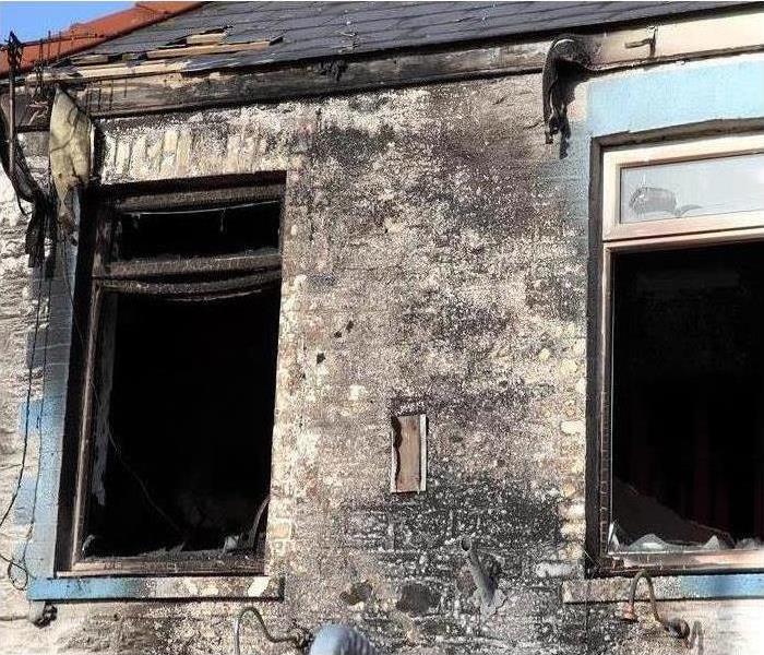 Exterior side of a house burned, window broken