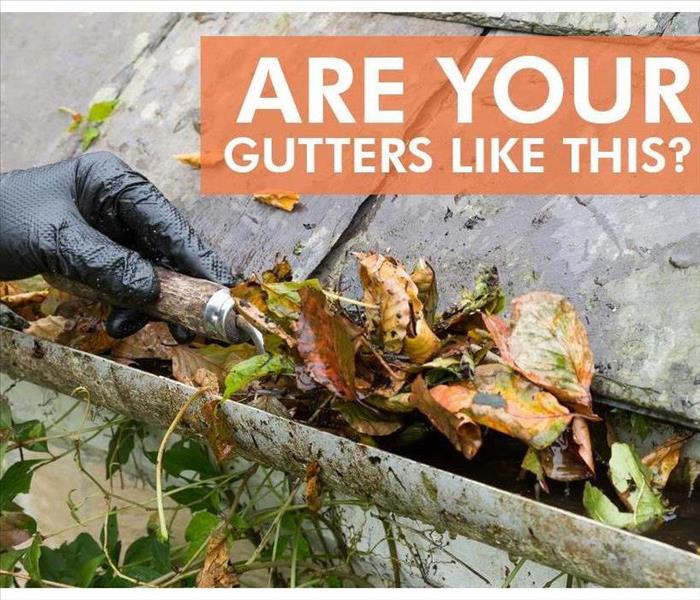 clearing blocked gutter of autumn leaves with trowel