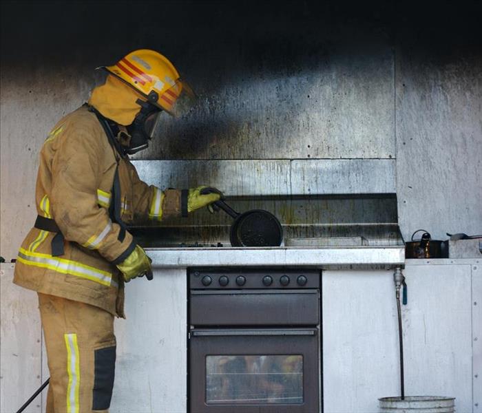 Fire fighter standing by a soot covered grill after a fire. 