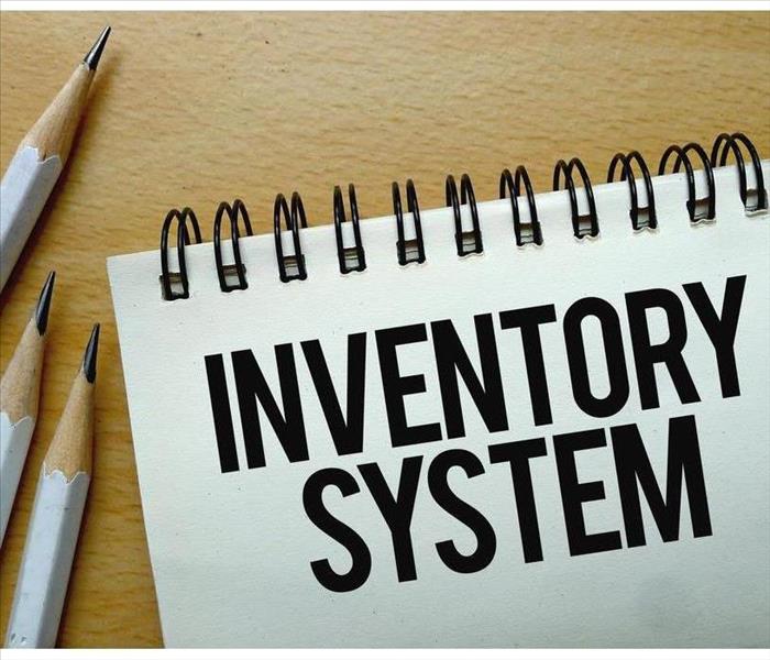 Notebook with the phrase INVENTORY SYSTEM  and three pencils